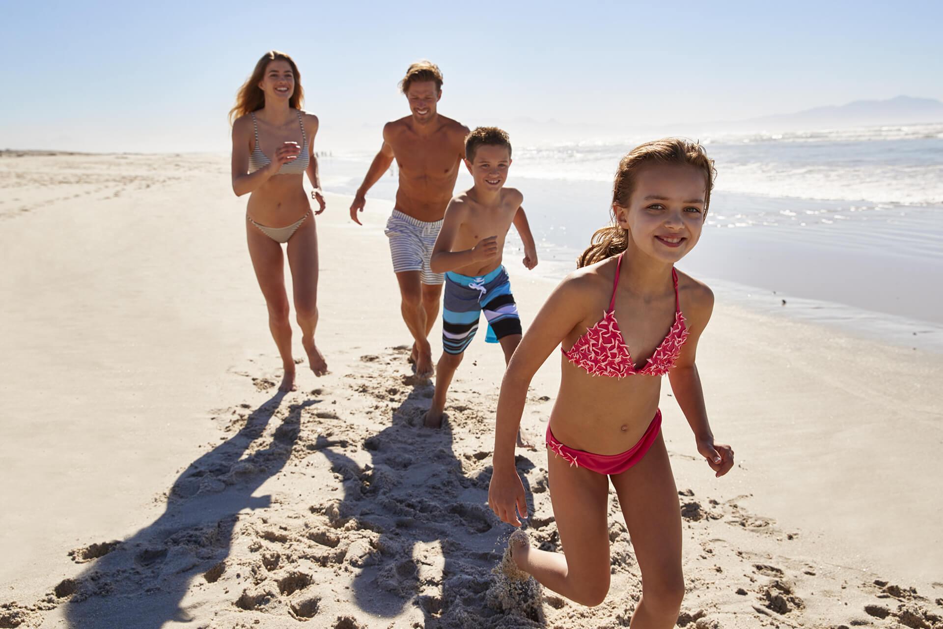 Happy family running on the beach on a sunny day.